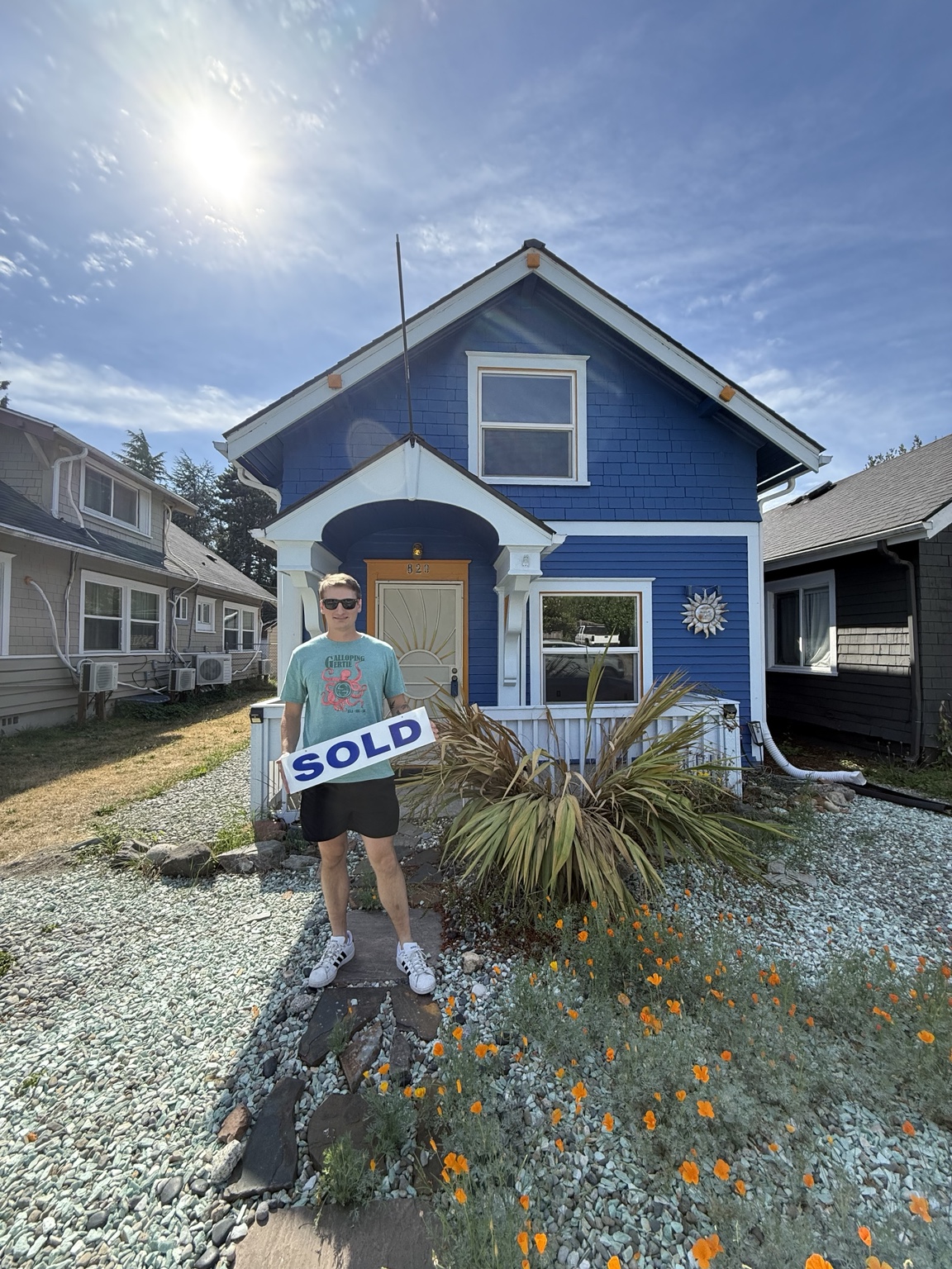 Homebuyer with a sold sign in front of a blue Tacoma house