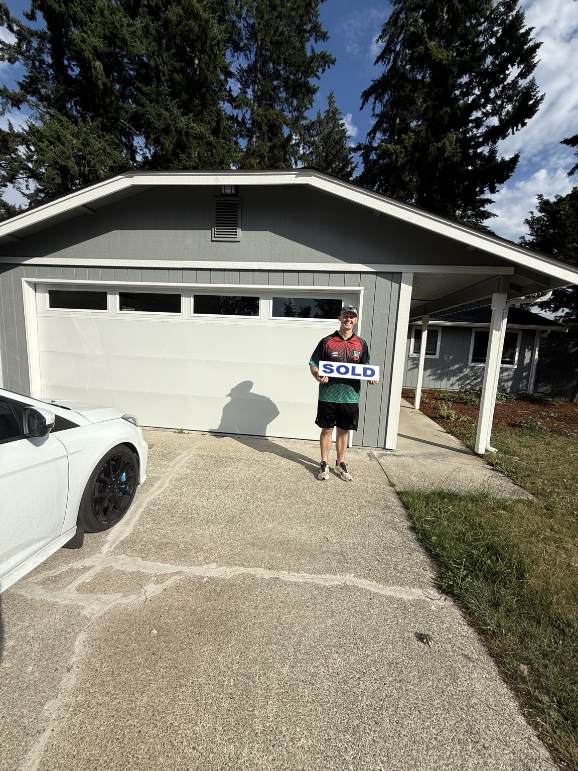 Homebuyer with a sold sign in front of a home